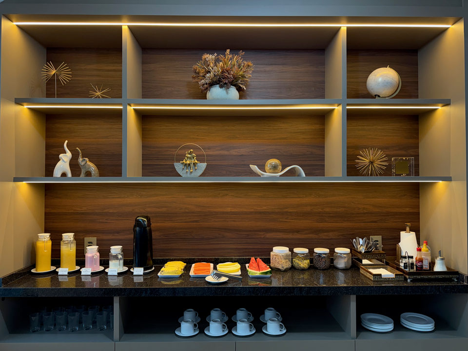 Estante com garrafas, geleias e as louças do café