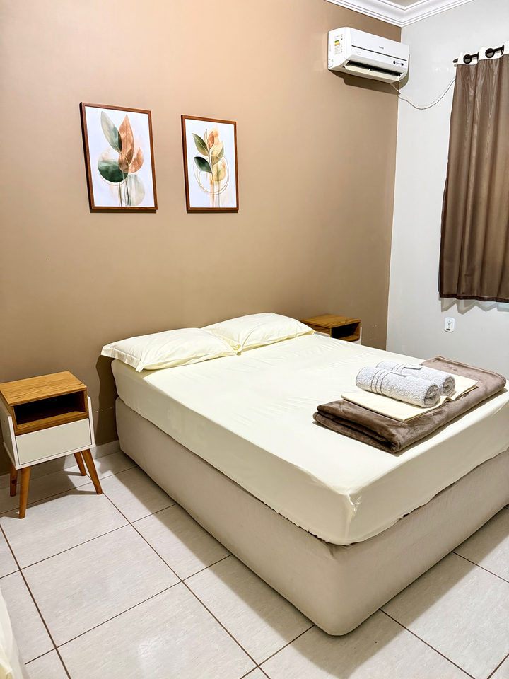 Cama de casal com dois quadros, ar-condicionado e cortina marrom