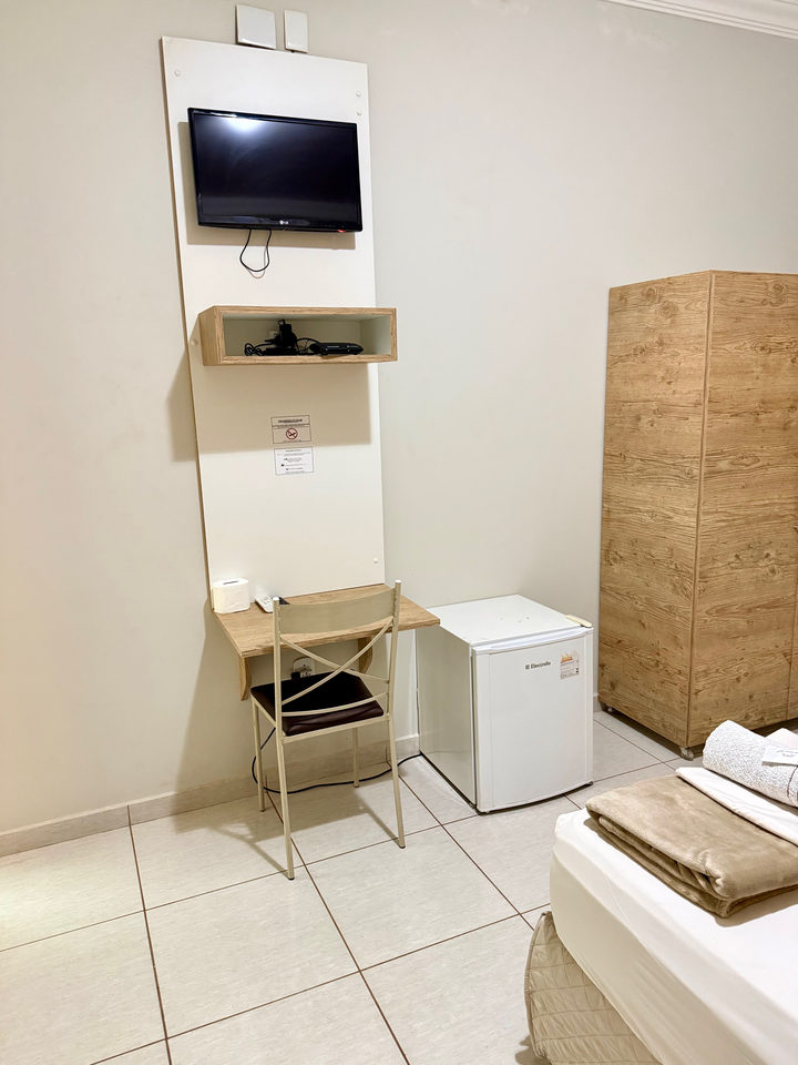 Televisão no painel, escrivaninha, frigobar e guarda-roupa